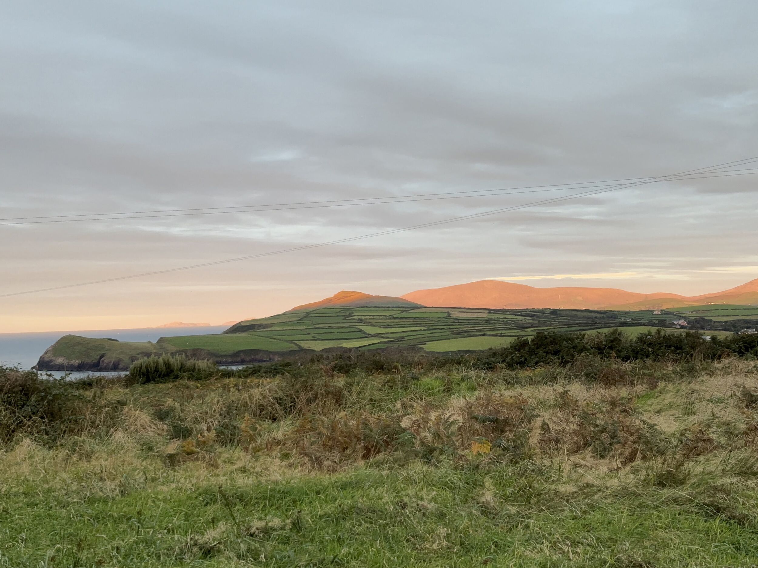 A rural landscape with rolling hills and a body of water in the distance.