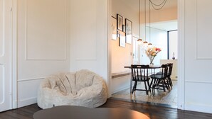 A modern living room with a bean bag chair, a dark round table, and a dining area with chairs and a vase of flowers. - Cosy Courtyard House Hasselt (Hasselt)