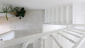 A white wooden staircase with a railing, a white wall, and a hanging plant. - Cosy Courtyard House Hasselt (Hasselt)