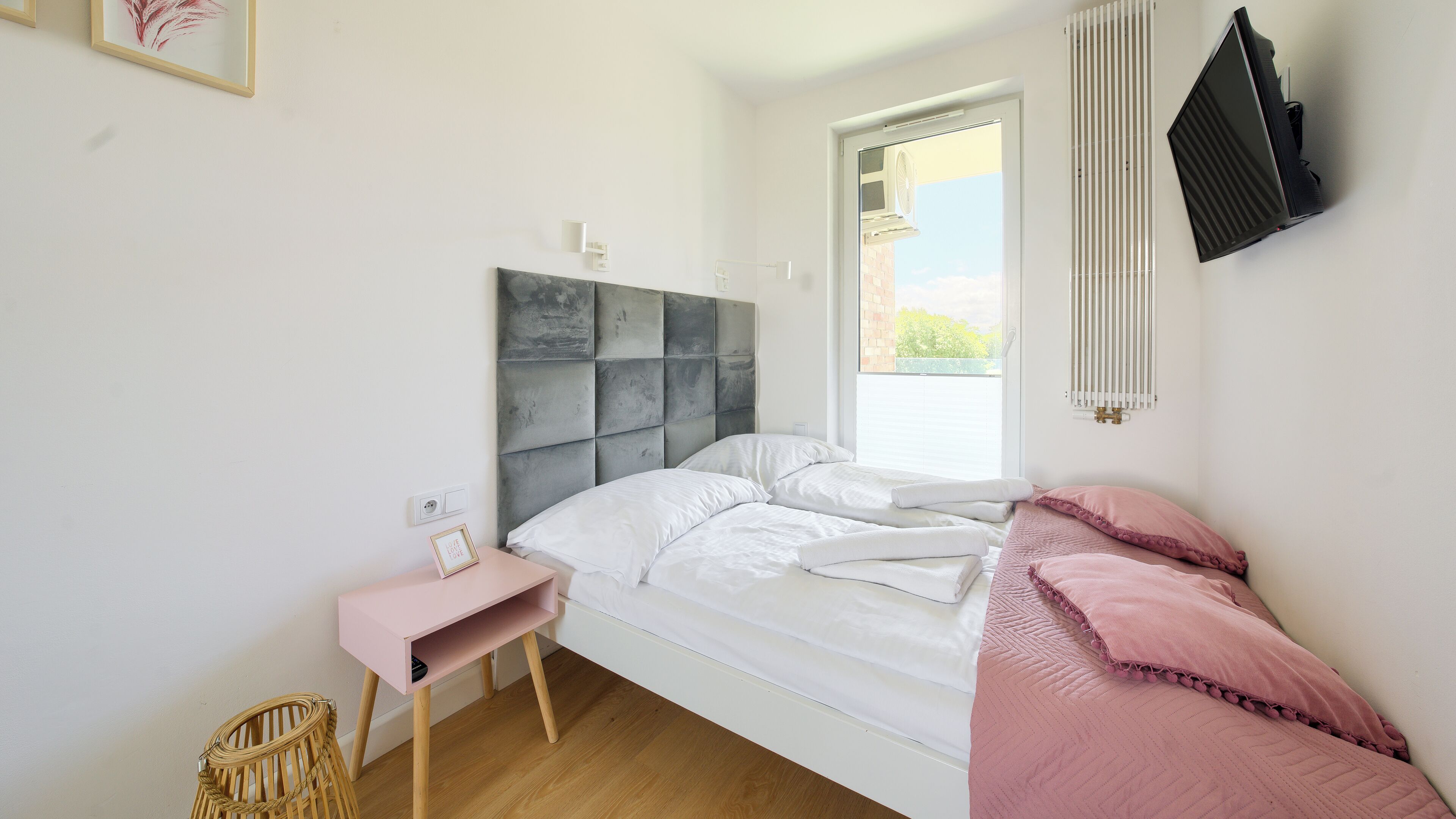 A bedroom with a bed, bedside table, chair, and a window with blinds.
