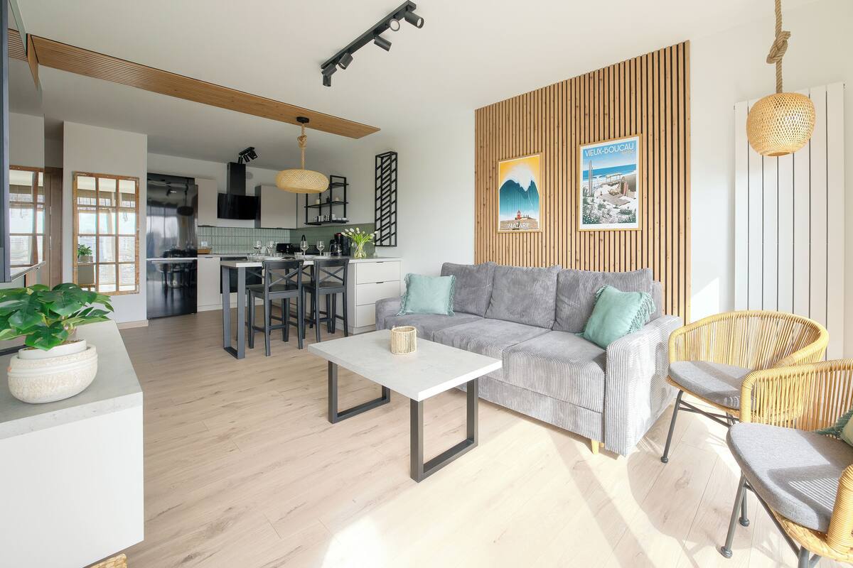 Una sala de estar moderna con un sofá, sillas, una mesa de comedor y una cocina al fondo.