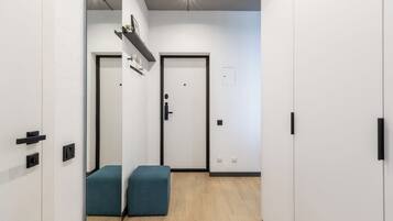 Un couloir avec un banc, une porte et une étagère sur laquelle sont posés divers objets.