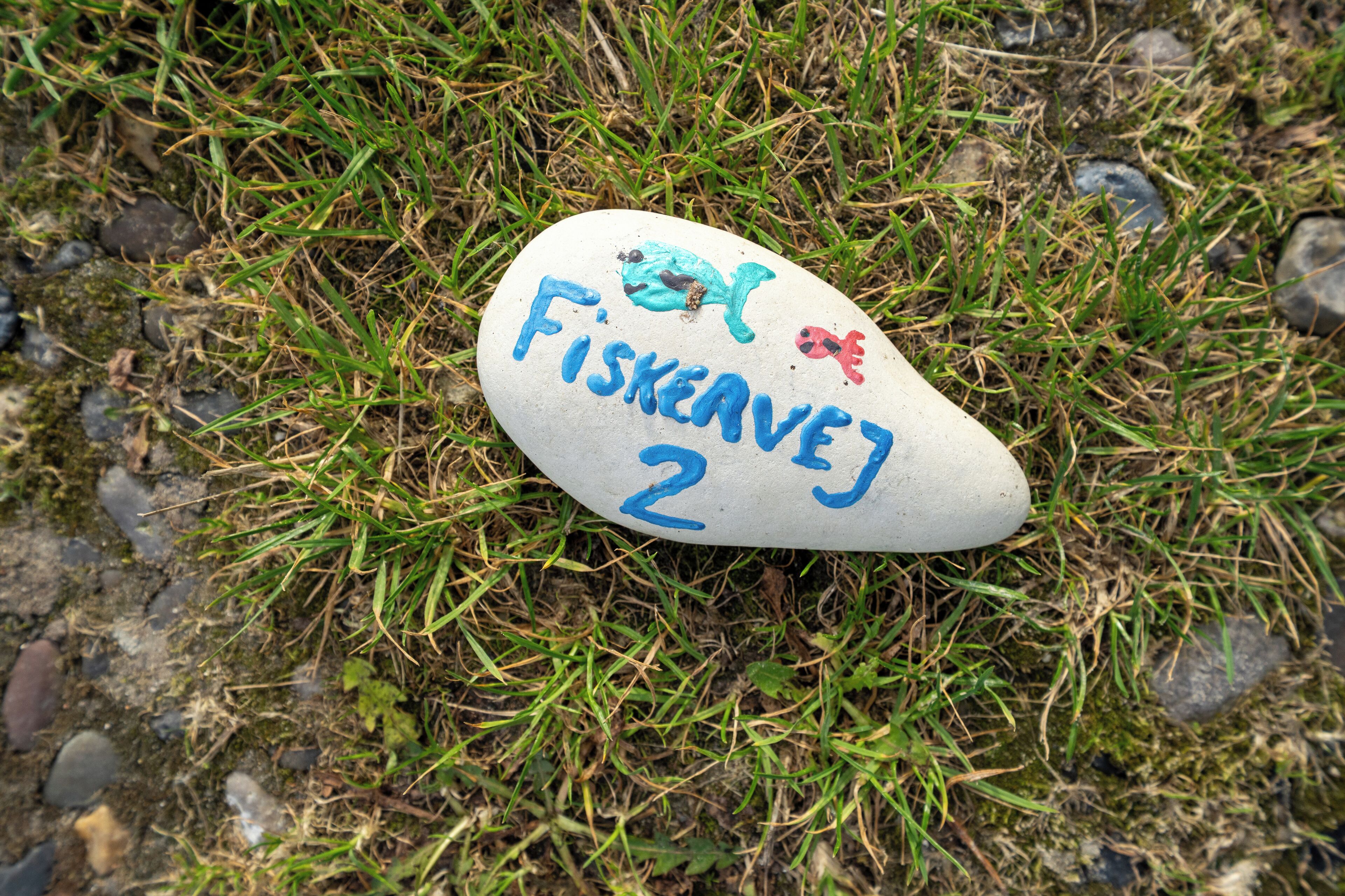 A stone with the text "Fiskervej 2" and a drawing of a fish.