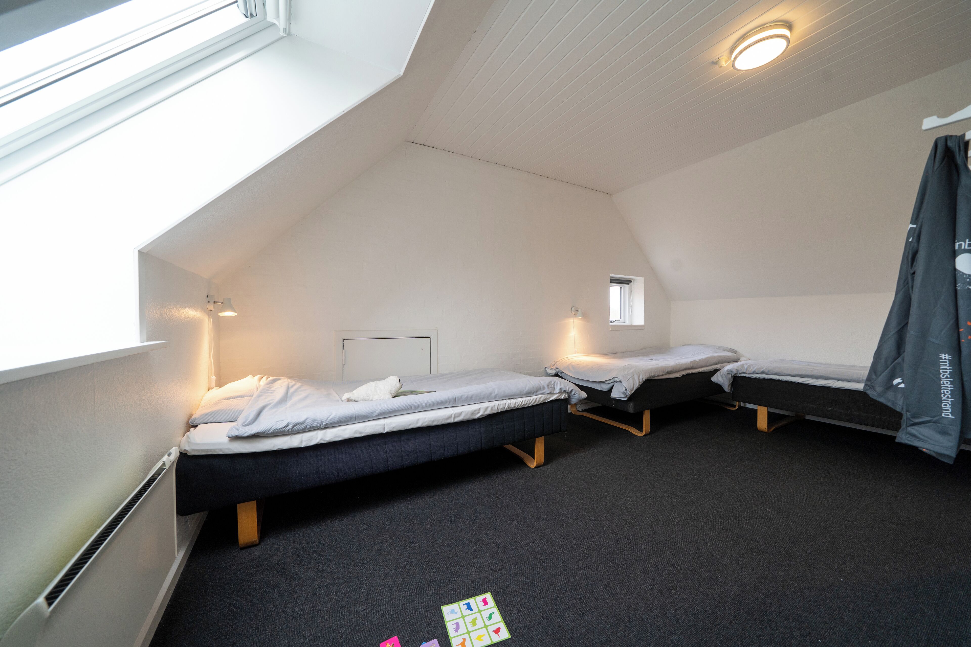 Un dormitorio con dos camas individuales, una ventana pequeña y un radiador.