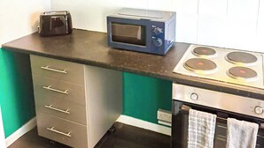 Una cocina compacta equipada con microondas, tostadora, estufa y horno pequeño.