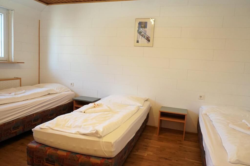 Une chambre de dortoir avec deux lits, une petite table et une fenêtre.