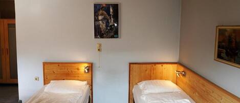 A room with two wooden beds, a nightstand, and a painting on the wall.