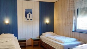 A room with two beds, a small table, and a wall-mounted picture. - Pension zur Rose (Schoenaich)
