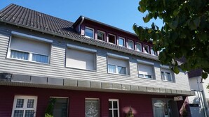 A two-story building with a red facade and a grey roof. - Pension zur Rose (Schoenaich)