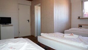 A hotel room with two beds, a television, and a door leading to another room. - Pension zur Rose (Schoenaich)