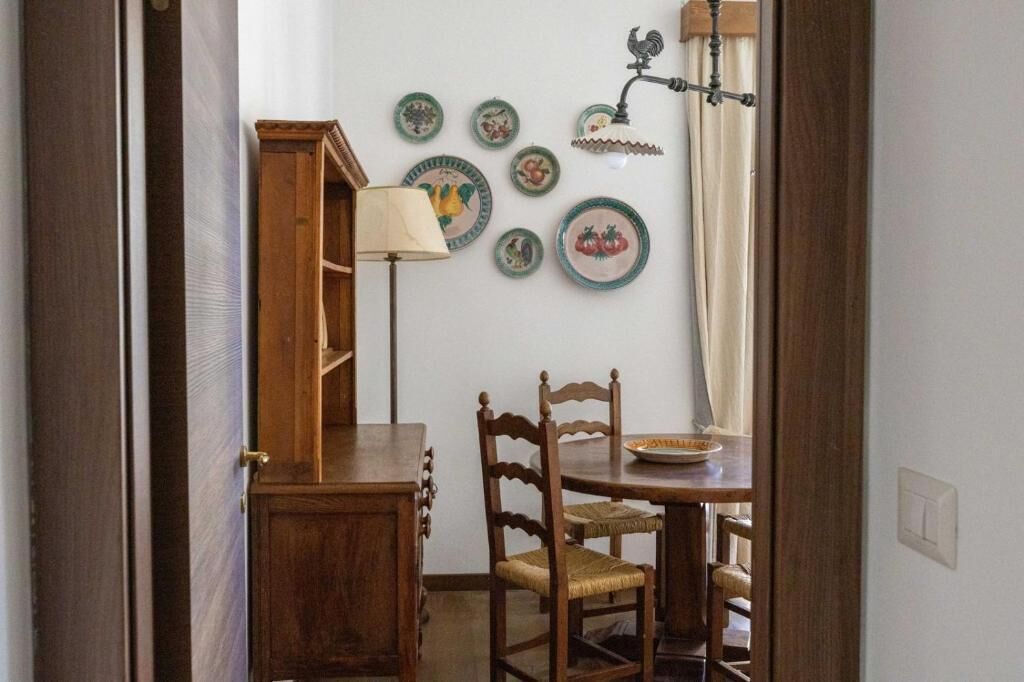 Un coin repas avec une table et des chaises en bois, une lampe et des assiettes décoratives accrochées au mur.