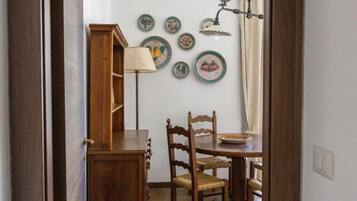 Un coin repas avec une table et des chaises en bois, une lampe et des assiettes décoratives accrochées au mur.