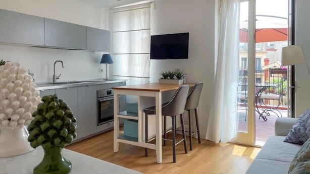 A modern kitchen with a dining area, a flat-screen TV, and a sliding glass door to an outdoor patio.