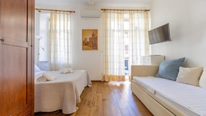 A room with two beds, a television, and a painting on the wall.
