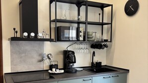 A modern kitchen with a built-in microwave, coffee machine, and a glass shelf with kitchenware. - Oasis of relaxation in the heart of Altavilla Milicia, located between Palermo and Cefalù. (Altavilla Milicia)