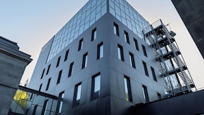 Un edificio moderno con facciata in vetro e una scala antincendio sul lato destro.