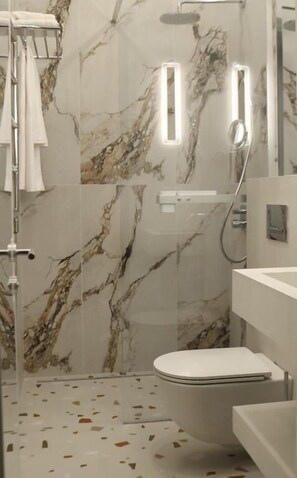 A modern bathroom with a marble backsplash, a glass shower enclosure, and a white toilet. - Moselle Armenia Wellness & Medical SPA  (Jermuk)