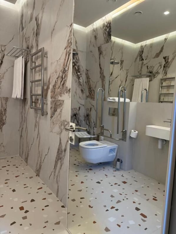 A modern bathroom with a marble wall, a freestanding bathtub, a toilet, and a sink. - Moselle Armenia Wellness & Medical SPA (Jermuk)