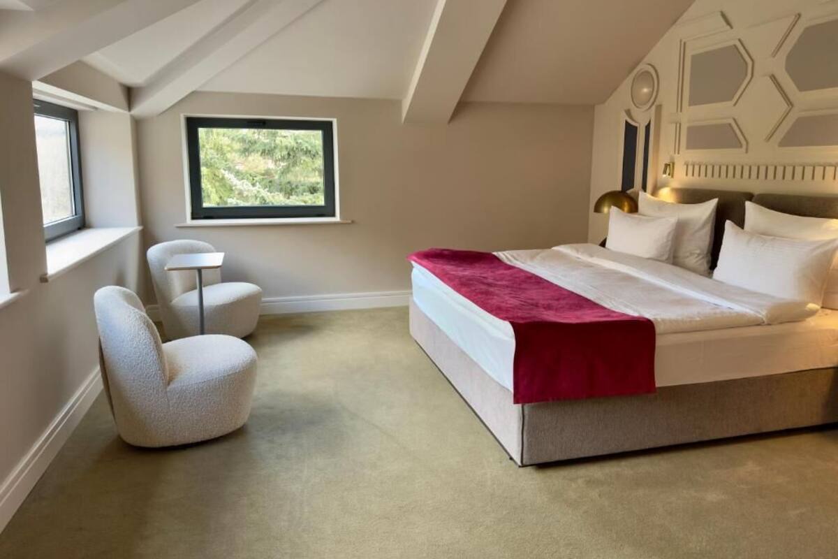 Un dormitorio con una cama grande, una ventana, una silla y una mesita.