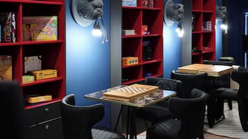 A room with red shelving units, black chairs, and a chessboard on a glass table.