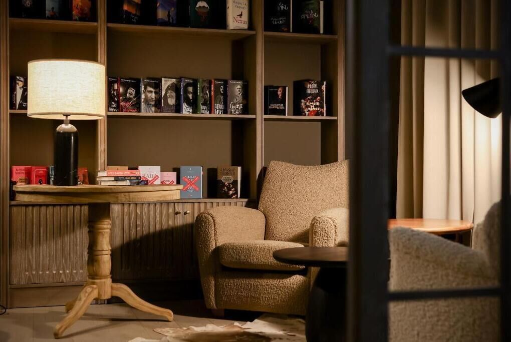 A cozy reading nook with a bookshelf, a lamp, and a comfortable armchair.