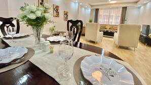 A dining area with a table set for four, chairs, a vase with flowers, and artwork on the wall. - Top Location & Spacious 3BR Apartment in Prime Bole, City View, Walk to Airport (Addis Ababa)