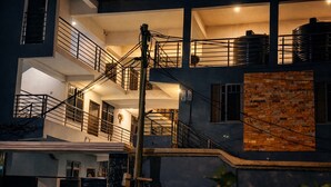 A multi-story building with balconies, staircases, and large water tanks on the roof. - Cozy 1-bedroom studio in tranquil Weija with AC comfort (Weija)