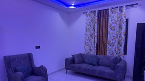 A living room with a sofa, armchair, and patterned curtains. - Cozy 1-bedroom studio in tranquil Weija with AC comfort (Weija)
