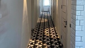 A hallway with patterned flooring, recessed lighting, and doors on both sides. - Hectors Hotel (Kokand)