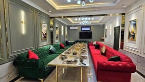 A spacious living room with a long dining table, two sofas, and a chandelier. - Hectors Hotel (Kokand)