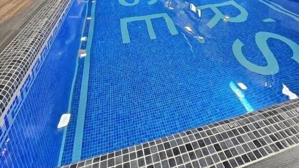 An indoor swimming pool with clear blue water, tiled walls, and a modern design. - Hectors Hotel (Kokand)