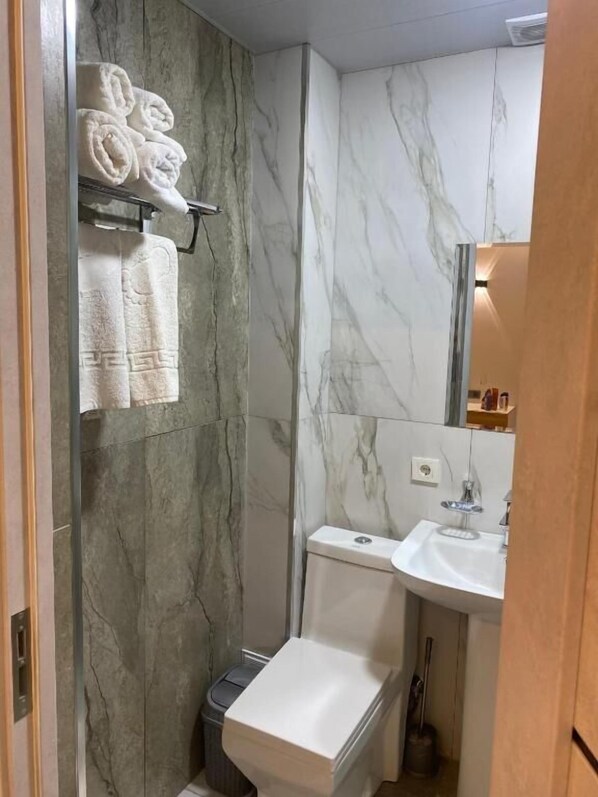 A bathroom with a toilet, sink, and towel rack. - Hectors Hotel (Kokand)