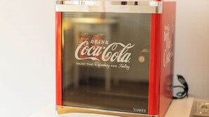 En röd och silverfärgad försäljningsautomat för Coca-Cola med texten "DRICK Coca-Cola och NJUT av den uppfriskande, nya känslan" på framsidan.