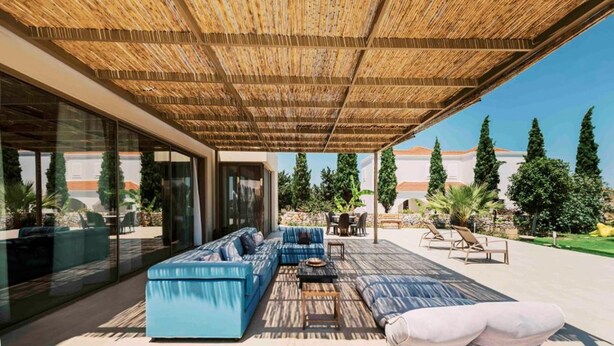 Un espacio al aire libre techado con una zona de estar con un sofá azul, una mesa de comedor y una pérgola.