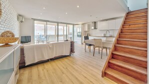 A modern kitchen with white cabinets, a wooden staircase, and a dining area with a table and chairs. - Duplex 2 bedrooms Terrace Sea view A2B024 (Cannes)