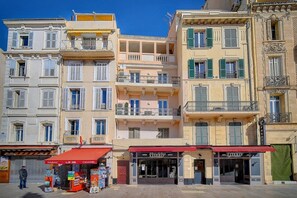 A row of multi-story buildings with balconies, storefronts, and a clear blue sky. - 2-Bedroom Duplex with Terrace and Ocean View A2B024   (Cannes)