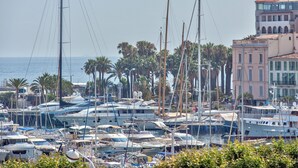 A marina with multiple yachts docked, surrounded by palm trees and buildings with Mediterranean architecture. - Duplex 2 bedrooms Terrace Sea view A2B024 (Cannes)