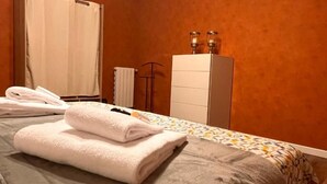 Ein Hotelzimmer mit einem Bett, einem weißen Kleiderschrank und einem Handtuchhalter mit Handtüchern.