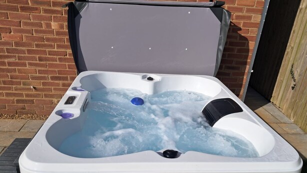 A hot tub with a gray exterior, a white interior, and a blue drain cover. - 3 Bed Cottage - Sleeps 5 - Pets - Hottub - Garden (King's Lynn)