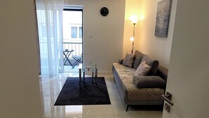 A modern living room with a sofa, a black rug, a floor lamp, and a painting on the wall. - Charming apt With Balcony in the Heart of Split (Split)
