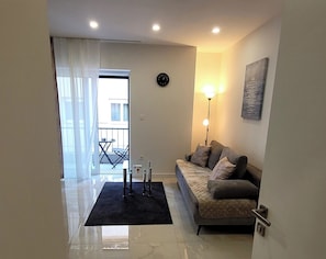Ein modernes Wohnzimmer mit einer Couch, einem schwarzen Teppich, einer Stehlampe und einem Bild an der Wand.