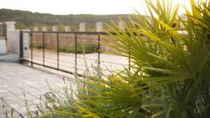 A rooftop terrace with a metal railing, potted plants, and a view of a distant landscape. - Adriatic Pearl (Solta)