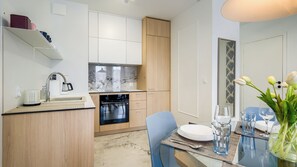 Apartment (114) | Privékeuken | Een koelkast, een kookplaat, een waterkoker, kookgerei, borden en bestek