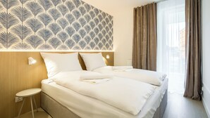 A hotel room with a large bed, two pillows, a bedside table, and a patterned headboard. - Apartamenty Sun & Snow West Park (Kołobrzeg)
