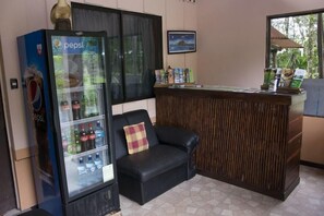 Un área de recepción con un refrigerador de Pepsi, un sofá de cuero negro y un mostrador de madera.