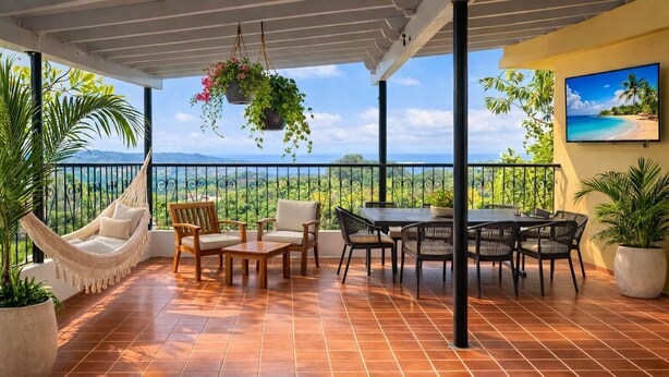 A covered patio with a view of the ocean, outdoor furniture, and hanging plants. - Peaceful Morovis Retreat – Private Terrace with Scenic Views (Morovis)
