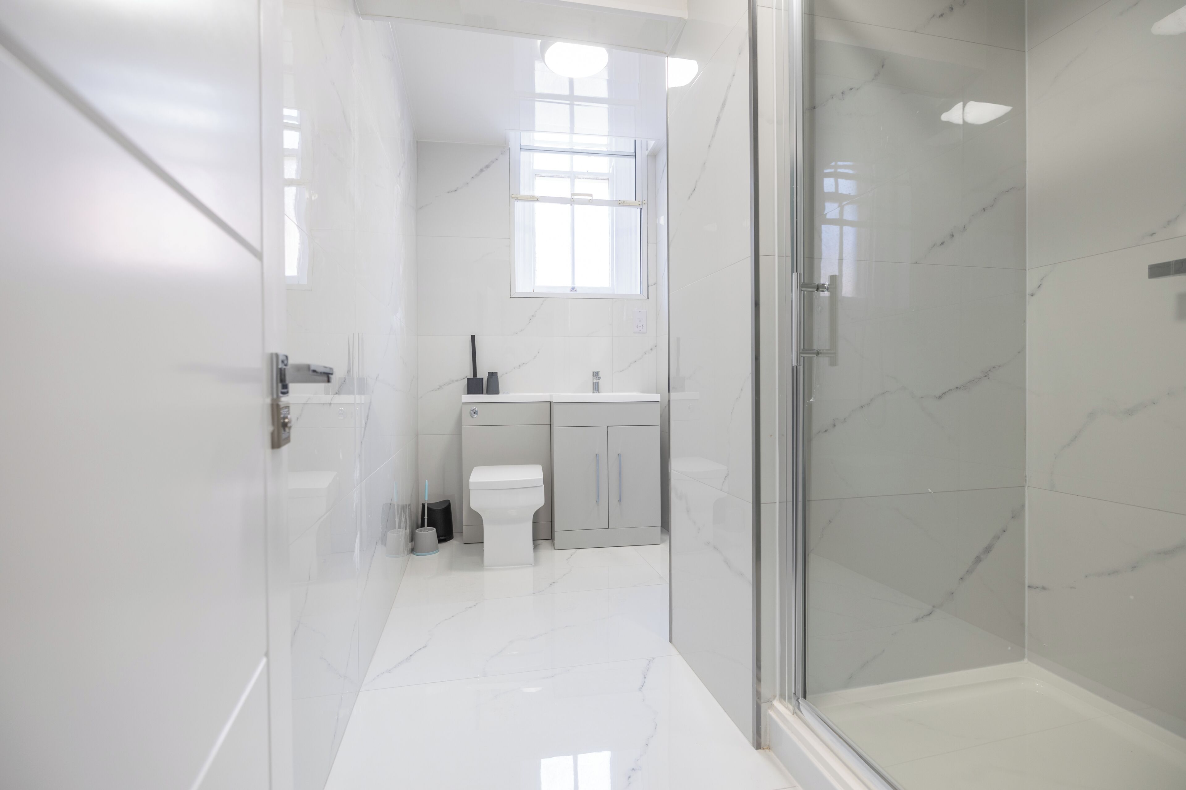 A modern bathroom with a glass shower enclosure, a toilet, and a sink with a mirror above.
