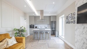 Una cocina moderna con una isla central, electrodomésticos de acero inoxidable y un patrón de suelo en espiga.