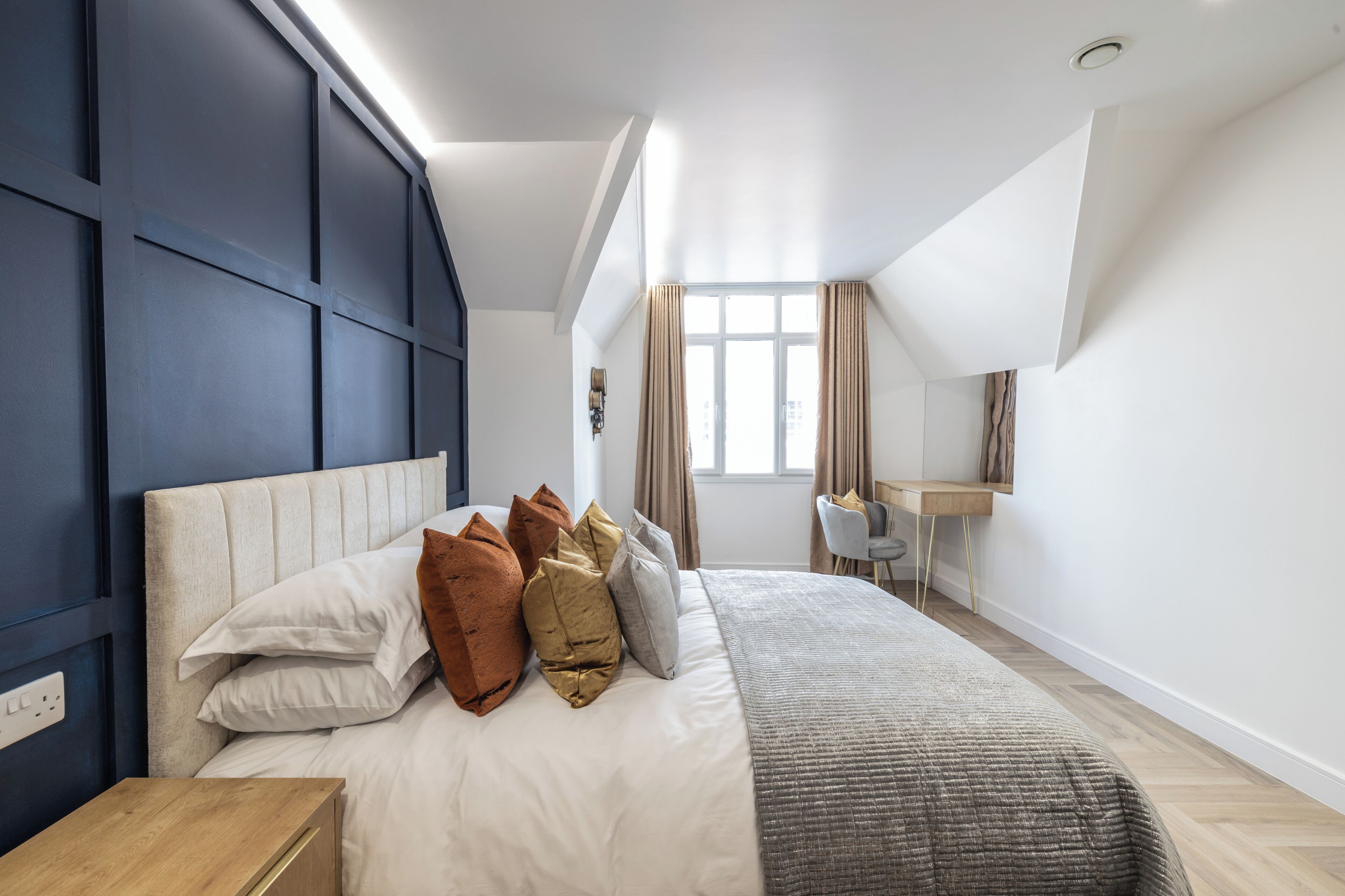A modern bedroom with a bed, a desk, and a window.