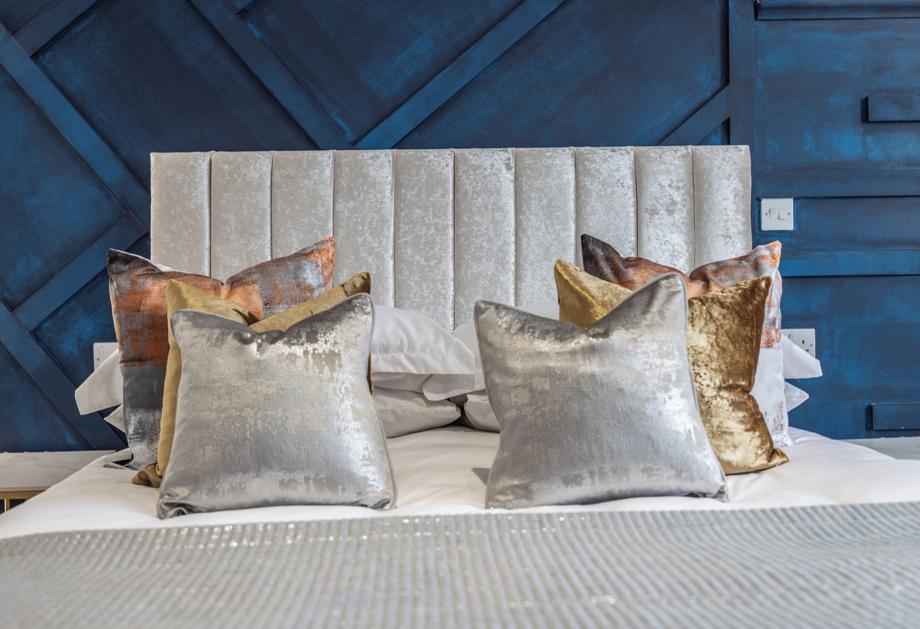 A bed with a headboard, pillows, and a striped bedspread.